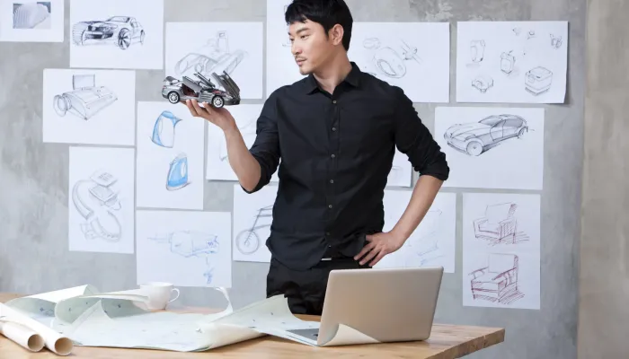 car-designer-holding-model-car-in-studio-2024-10-16-11-43-02-utc